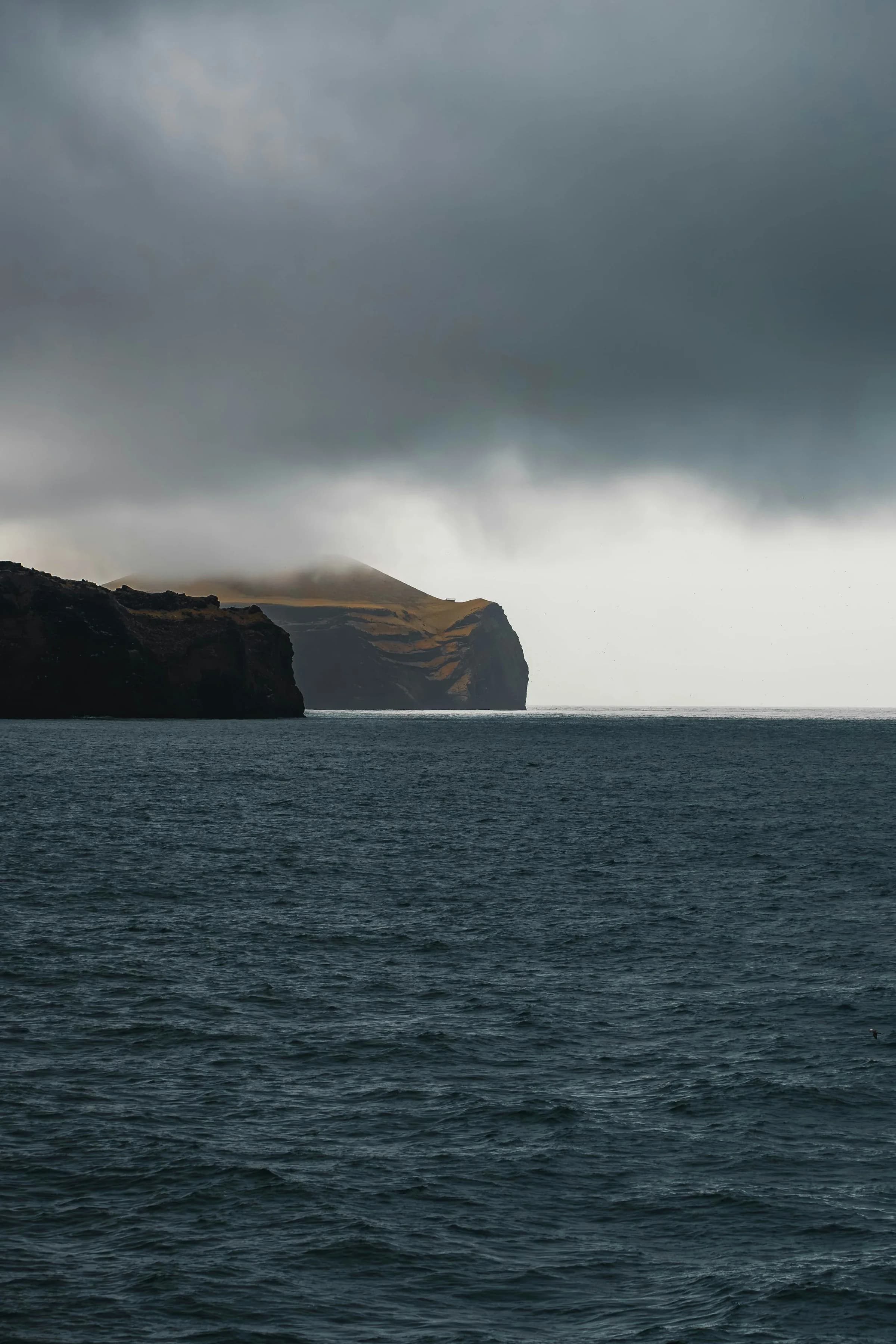 Dark ocean and rugged cliffs beneath heavy clouds