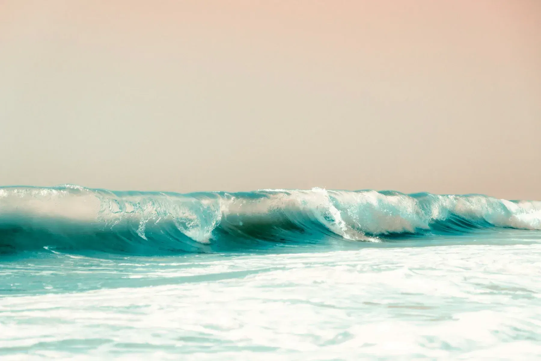 Teal ocean waves breaking into white foam