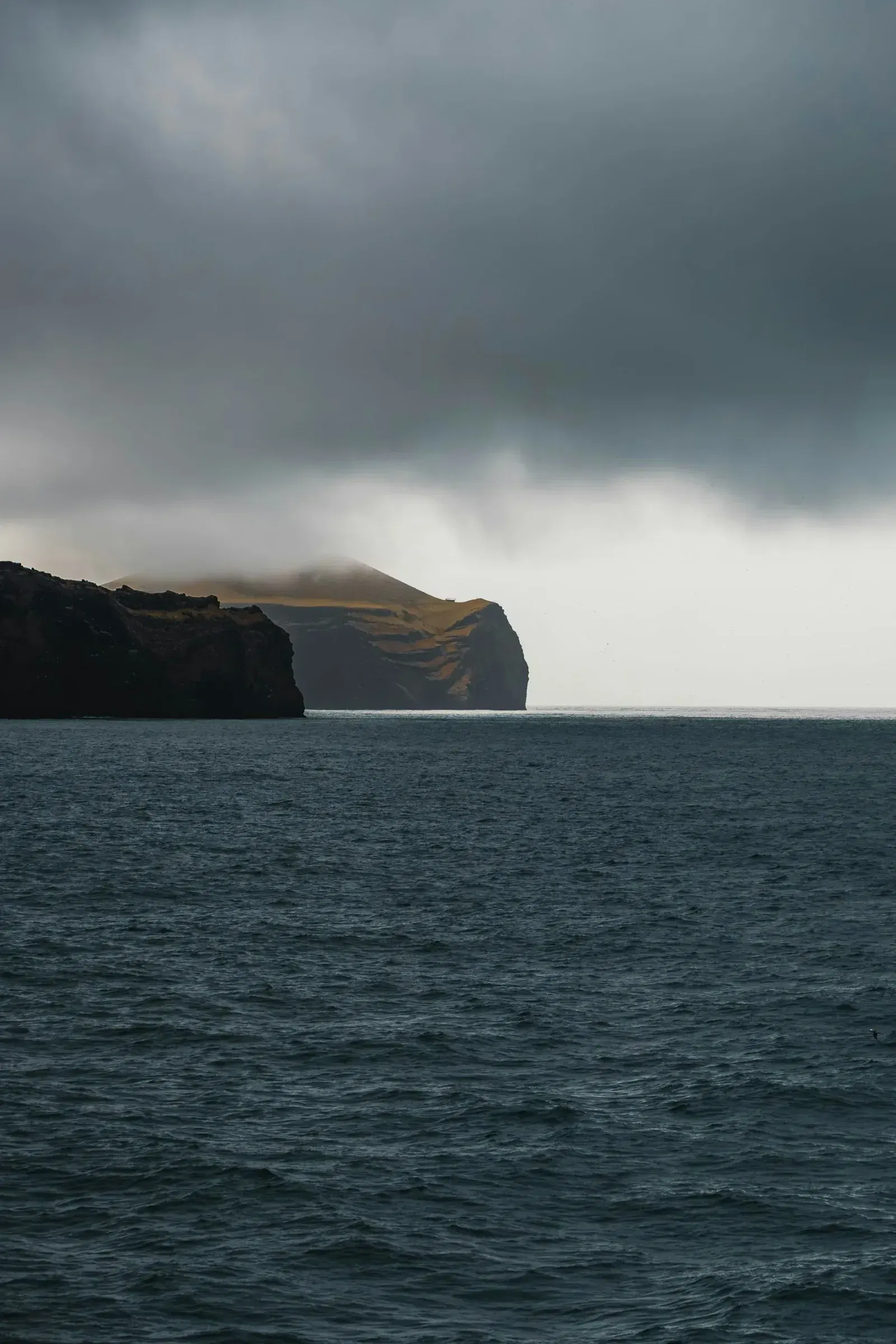 Dark ocean and rugged cliffs beneath heavy clouds