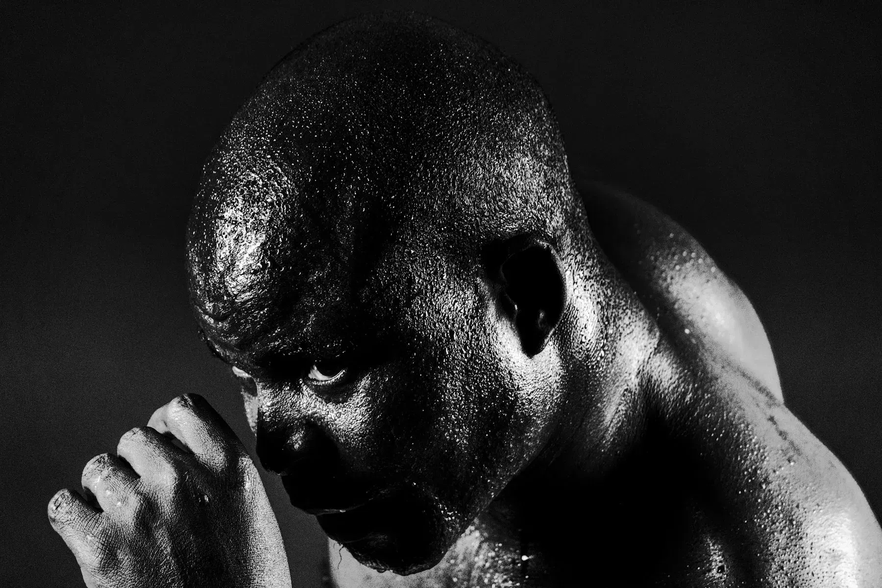 Monochrome portrait of a man with his head bowed and hands clasped