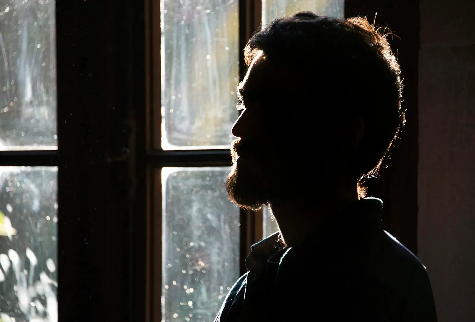 Silhouette of a man beside a bright window